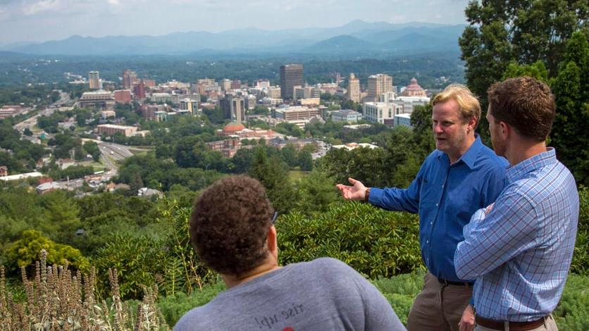 Professor talks to two students while overlooking City of Asheville skyline